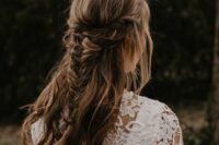 a cool boho half updo with a double braided halo and a fishtail braid and waves down is a cool idea for a boho bride