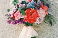 a cool colorful wedding bouquet in red, mauve, pink, blue and purple plus lace and blush ribbons hanging down