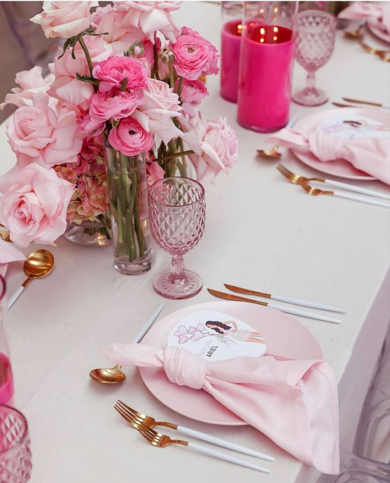 a cool pink wedding tablescape with blush plates and napkins, light and hot pink blooms, pink glasses and hot pink candleholders