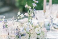 a delicate and chic spring garden wedding tablescape in pale blues, with pale blue textiles, a matching vase with neutral blooms, elegant and chic glasses