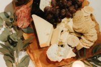 a deliciously styled charcuterie board with various cheese, salami, grapes and decorated with candles and greenery