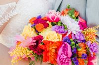 a fantastic colorful wedding bouquet of yellow, red, purple, hot pink blooms, berries and colorful ribbon is amazing