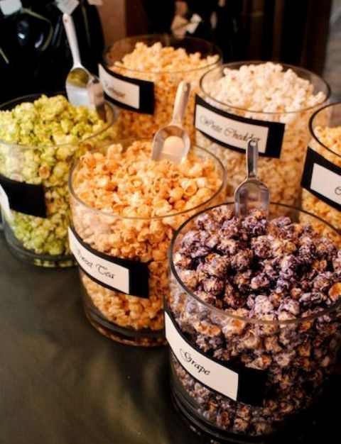 a flavored popcorn wedding bar with popcorn in glass jars and labels on them to mark the types
