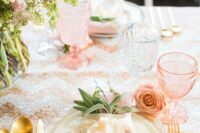 a glam wedding tablescape with a sequin table runner and pink glasses, gold cutlery and a pink floral centerpiece