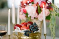 a golden pot with various fruit – grapes, pomegranates, apples and plums is a cute and lush centerpiece idea