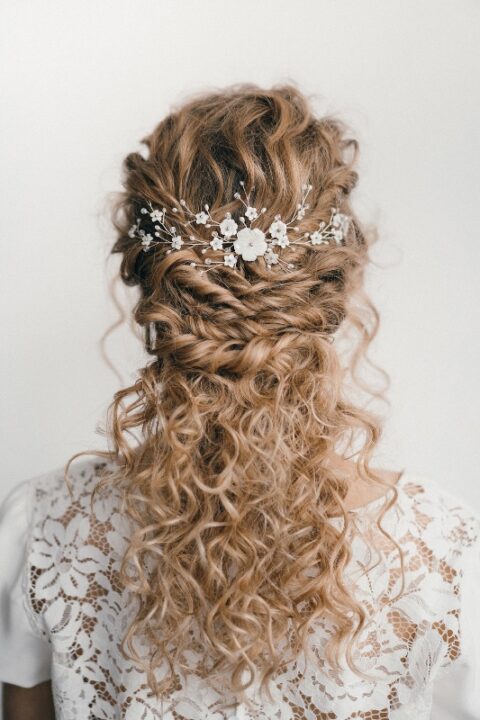 a gorgeous wedding half updo with natural curls – with twists accented with a floral hair piece and curls down
