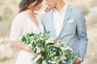 a groom wearing a pale blue pantsuit, a white shirt and no tie – a perfect wedding outfit for a coastal wedding