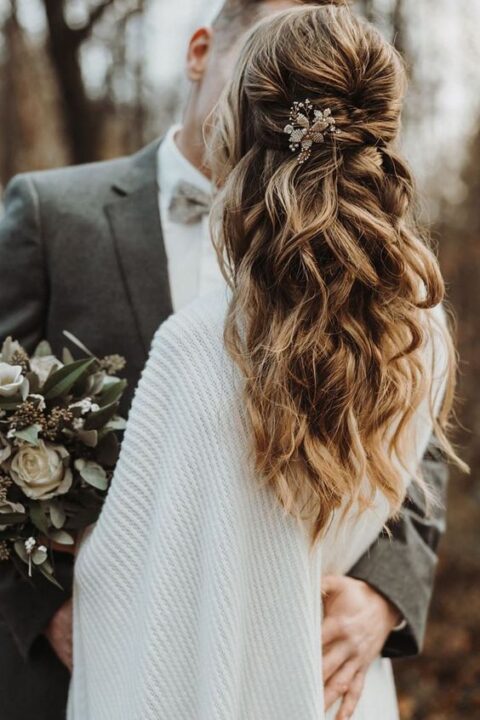 a lovely wedding half updo with twists and waves down, with locks framing the face and an embellished hairpiece