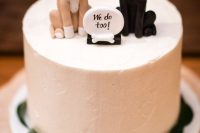 a lovely white wedding cake decorated with leaves and topped with dogs plus a sign is a cute idea for a dog-loving couple