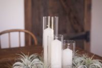 a lush pale air plant wedding centerpiece with pillar candles is a chic idea that is reasy to recreate