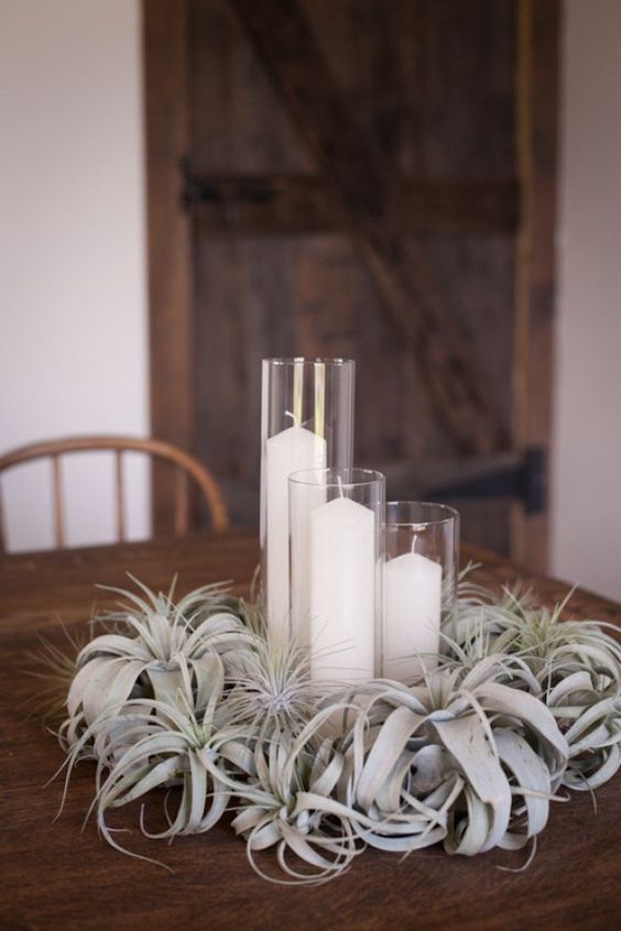a lush pale air plant wedding centerpiece with pillar candles is a chic idea that is reasy to recreate