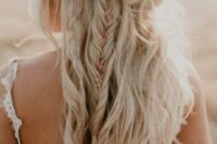 a messy boho wedding half updo with multiple twists, braids and waves and with some blooms tucked into the hair