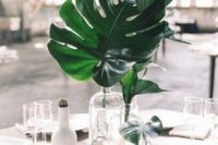 a modern centerpiece with clear glass vases and palm leaves is great to add a tropical touch to the table