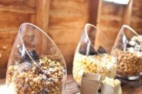 a modern wedding popcorn bar with angled glass jars and some cardboard bags for storing