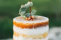 a naked wedding cake decorated with greenery and white blooms, with succulents and a copper wire monogram cake topper