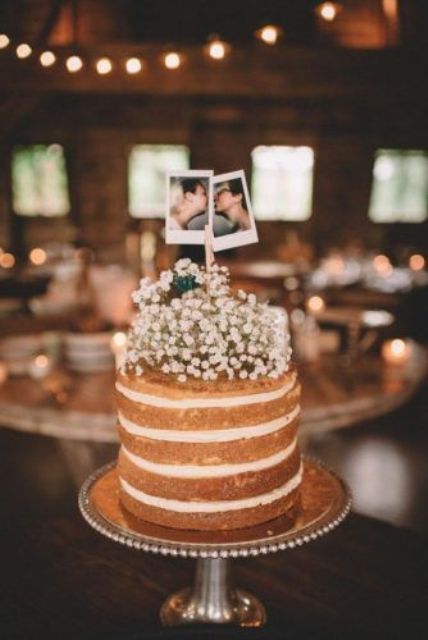 a naked wedding cake topped with baby's breath and with Polaroids of the couple is a simple and lovely idea
