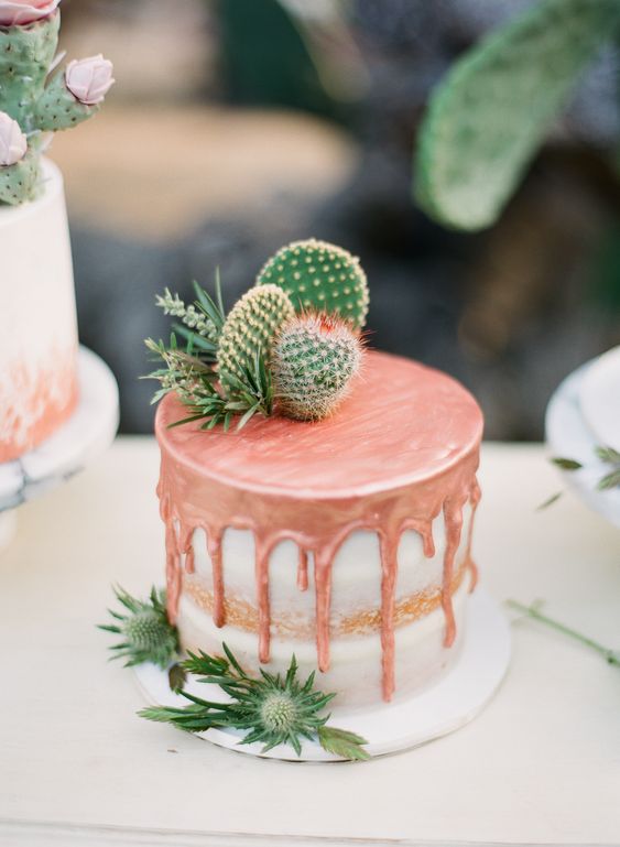 a naked wedding cake with copper drop, greenery and some cacti on top looks lovely