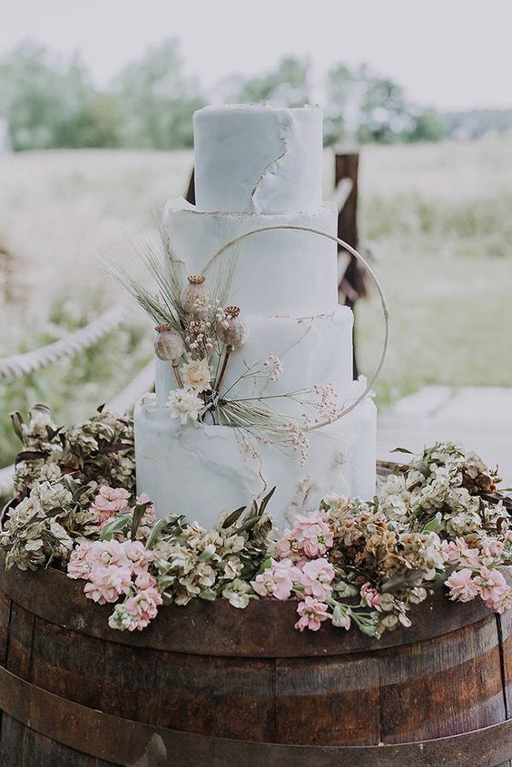 a pale blue textural wedding cake with a raw edge, an embroidery hoop decorated with pastel blooms