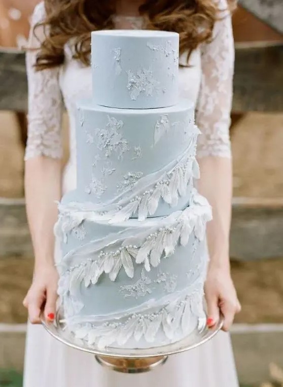 a pale blue wedding cake decorated with white brushstrokes, feathers and beads for a truly boho wedding