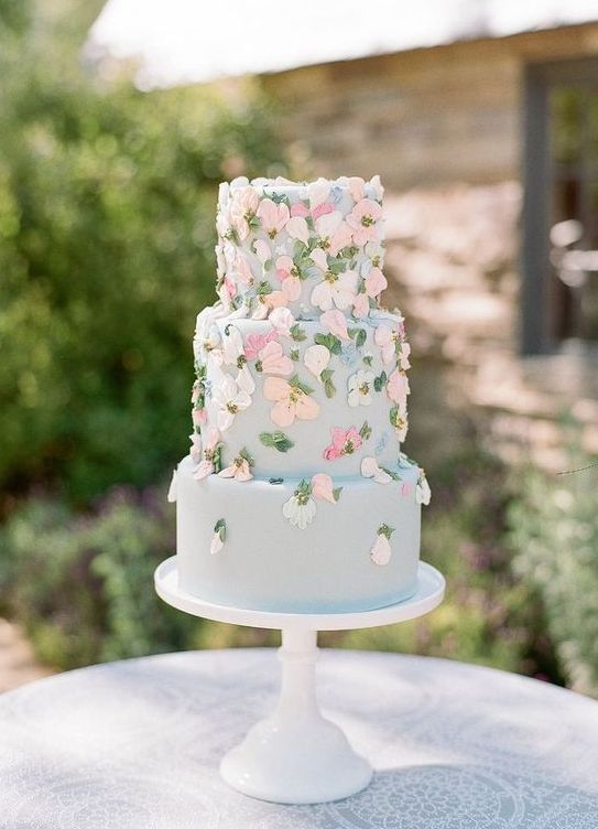 a pale blue wedding cake with pink and white sugar blooms is a beautiful and refined idea for a garden wedding
