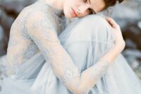 a pale blue wedding dress with an intricate lace top with long sleeves and a layered tulle skirt