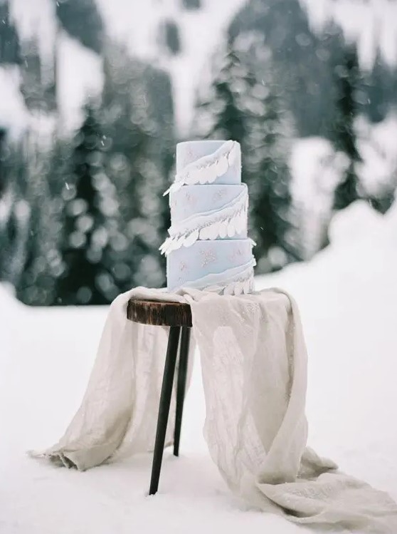 a pale blue winter wedding cake decorated with white feathers is a lovely and bold idea to go for