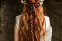 a pretty half updo with messy and textural braids on top and wavy locks down plus a greenery and fall floral crown with a burgundy bow