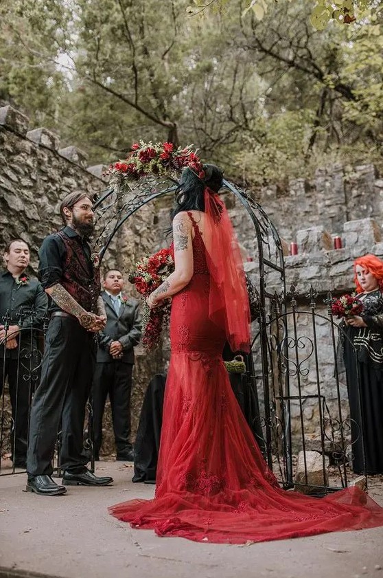 a red lace mermaid wedding dress with a train and an open back plus a red veil for a Gothic bride