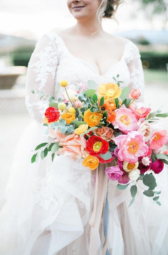 a refined and chic colorful wedding bouquet with yellow, red, pink and hot pink blooms, greenery and long neutral ribbons