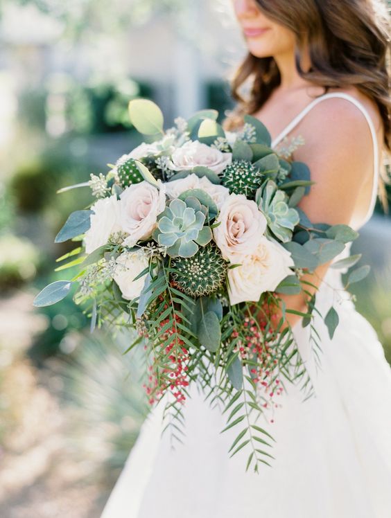 a romantic wedding bouquet with blush roses, greenery, berries, succulents and cacti is a gorgeous statement