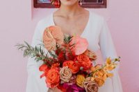 a saturated wedding bouquet of red, coffee-colored, yellow and pink blooms and greenery and long orange ribbon for a super bold wedding in summer