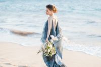 a super flowy and airy blue wedding dress with layers of fabric, a cutout back with ties and a train for a sea-loving bride