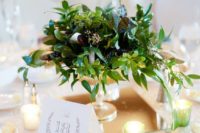 a textural greenery wedding centerpiece with various shades of green and dark green