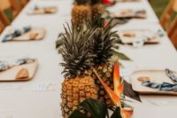 a tropical centerpiece version with pineapples and tropical blooms and leaves is a great idea for a modern tropical wedding