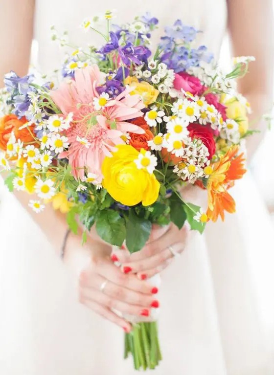 a very colorful wedding bouquet in pink, fuchsia, yellow and purple with a messy wildflower inspired look