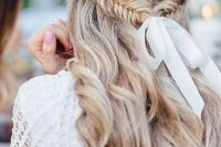 a wavy half updo with a fishtail braid secured with a white ribbon and a bow is a very relaxed boho idea