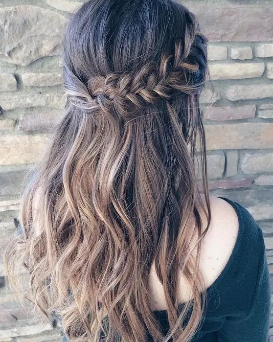 a wavy half updo with a thick fishtail braid on one side and twisted hair on the second