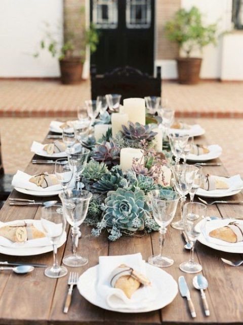 a wedding centerpiece of succulents of various shades and pillar candles is very stylish and chic