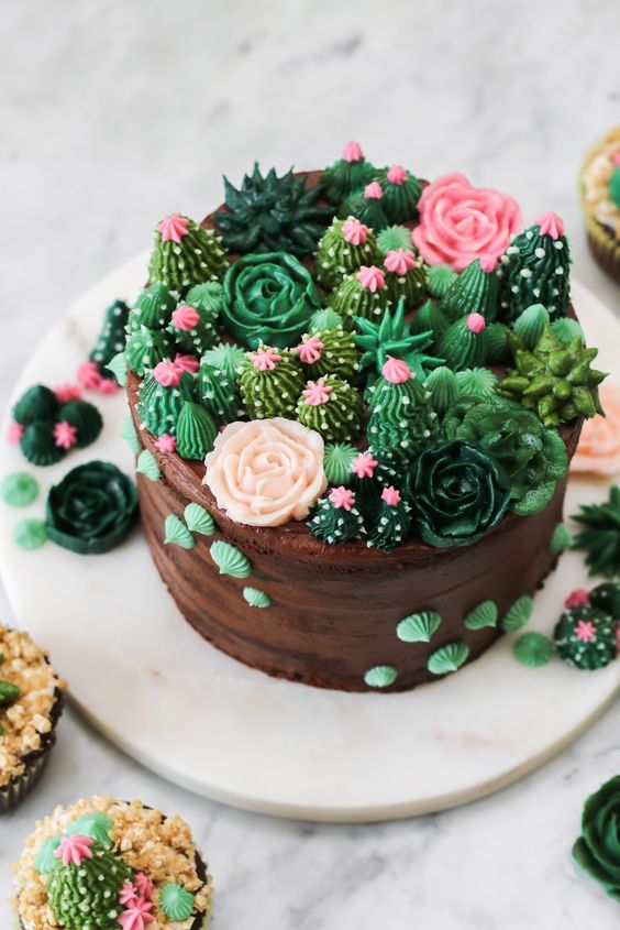 a whimsical chocolate wedding cake topped with sugar cacti and blooms looks very quirky and fun
