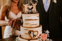 a white bark wedding cake decorated with pink and white blooms and with plywood deer silhouette cake toppers for a woodland wedding