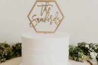 a white buttercream wedding cake topped with a hexagon cake topper with calligraphy is a lovely and modern idea