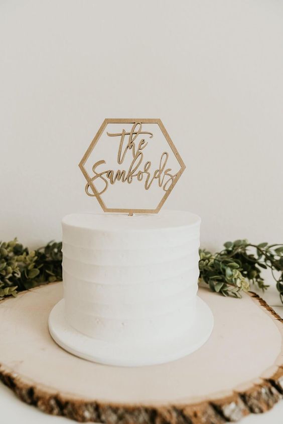 a white buttercream wedding cake topped with a hexagon cake topper with calligraphy is a lovely and modern idea