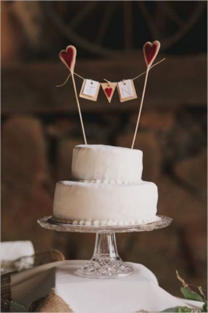 a white buttercream wedding cake with a fun cake topper - cookie pops holding a banner with monograms and a heart is a lovely idea