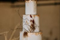 a white celestial wedding cake with gold foil, dried blooms, a moon and some twigs on top is a chic and lovely idea