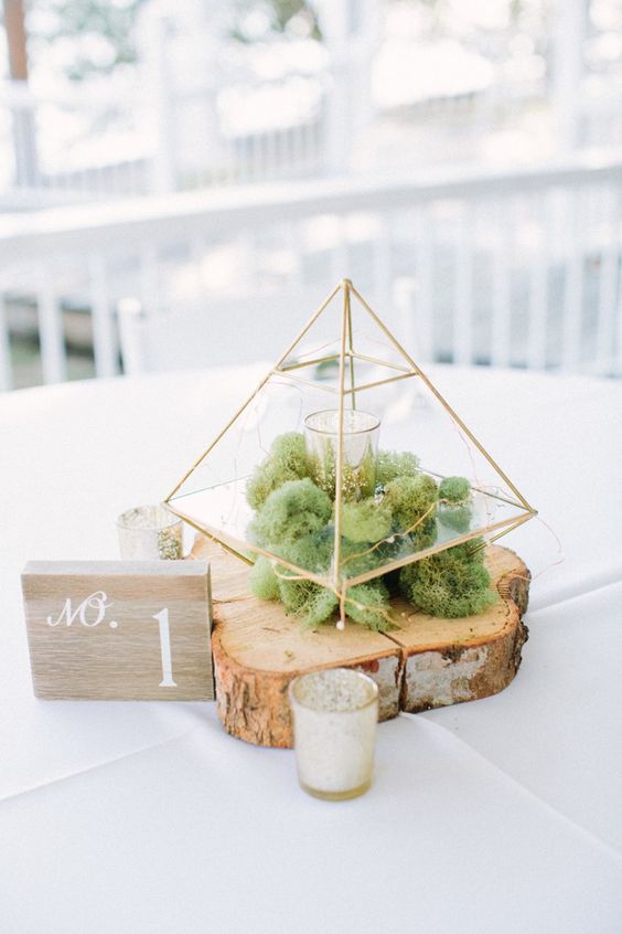 a wooden slice, moss, a terrarium with candles and a wooden table number for a rustic wedding
