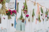 an overhead wedding installation with hanging bright blooms, greenery and cacti hanging downs looks creative
