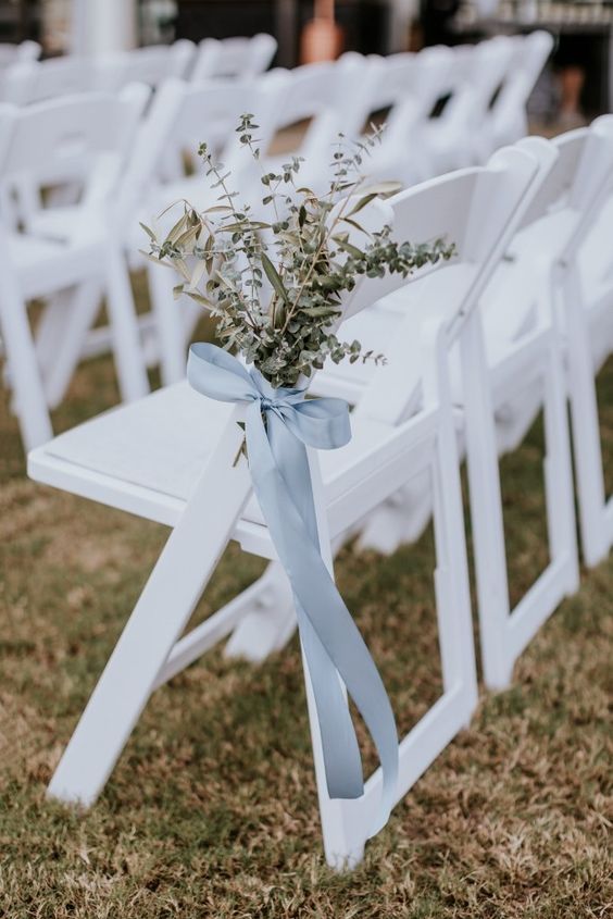white chairs decorated with eucalyptus and a pale ribbon bow are great for a relaxed wedding ceremony space