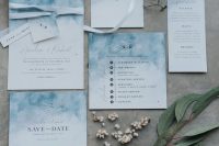 a beautiful blue and white wedding invitation suite with watercolors and black and navy prints, with white ribbon and pretty tags