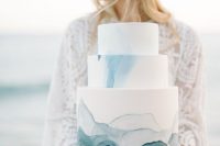 a beautiful coastal wedding cake in white, with blue waves, crystals looks very stylish and chic