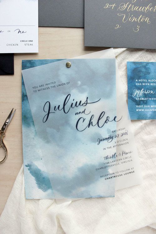 a beautiful modern beach wedding invitation suite with blue watercolors, grey envelopes and gold calligraphy plus black lettering